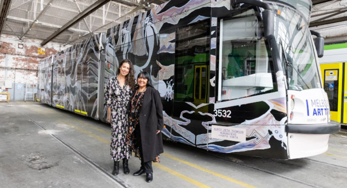 Two women standing in front of a painted tram carriage