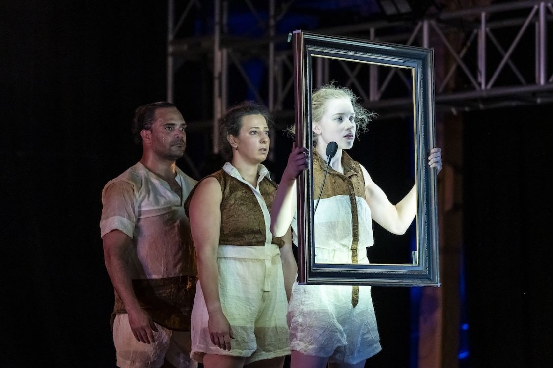 3 people standing on stage holding wooden frames