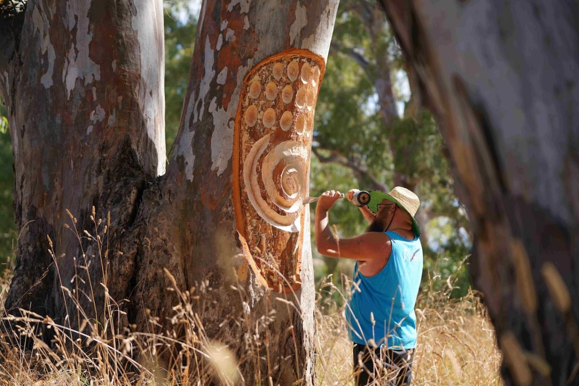 two men carving in a tree trunk
