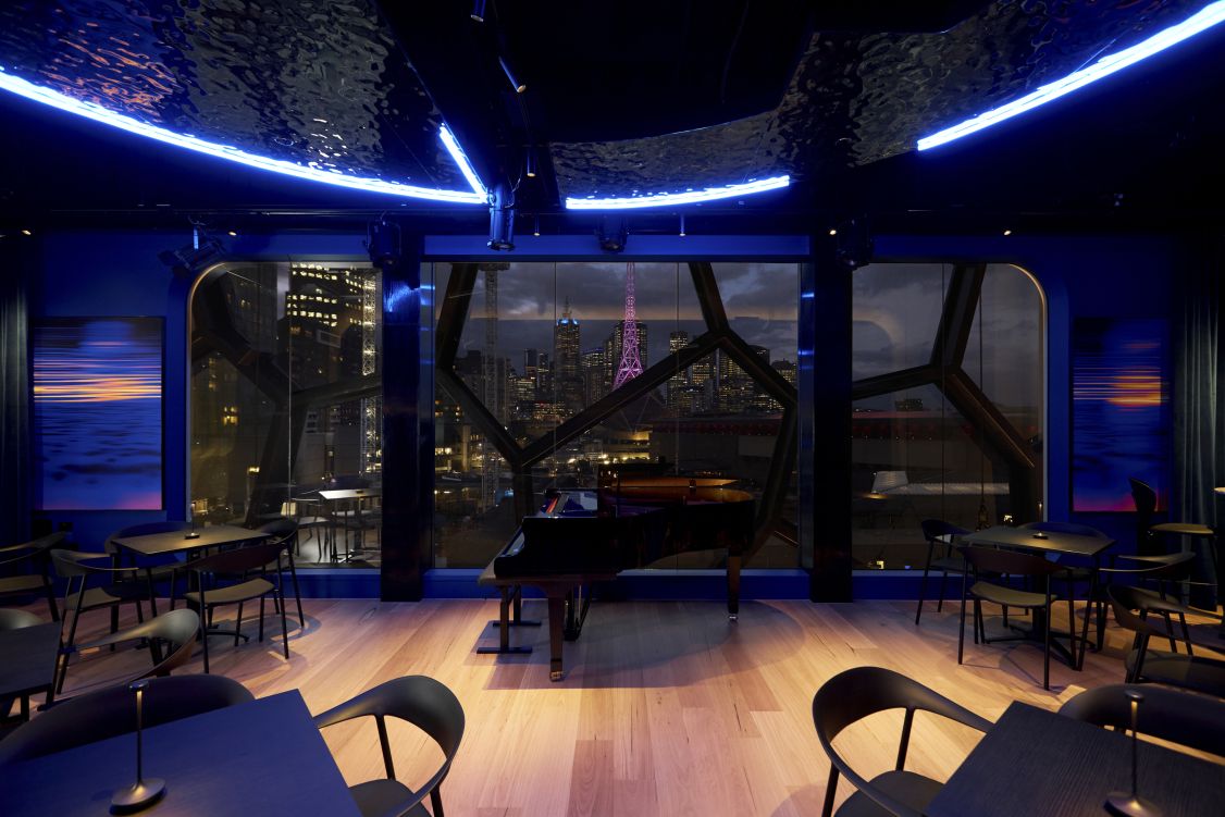 view of a piano in front of large windows overlooking a skyline