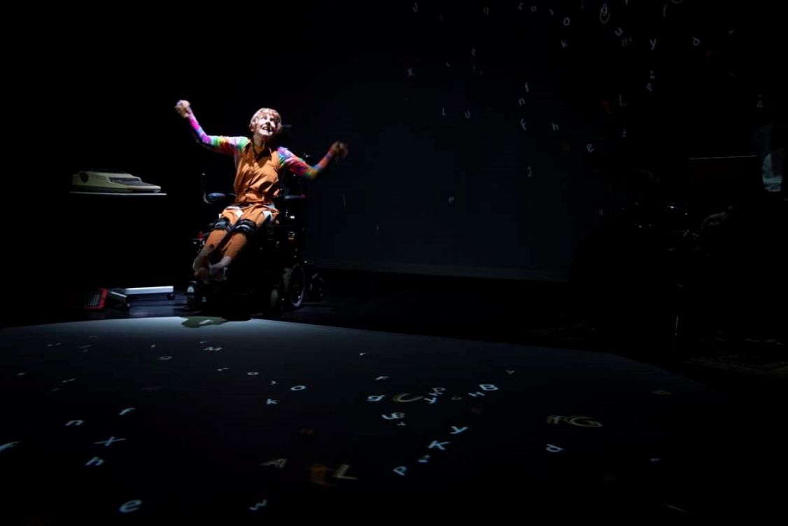 woman sitting in wheelchair on a dark stage